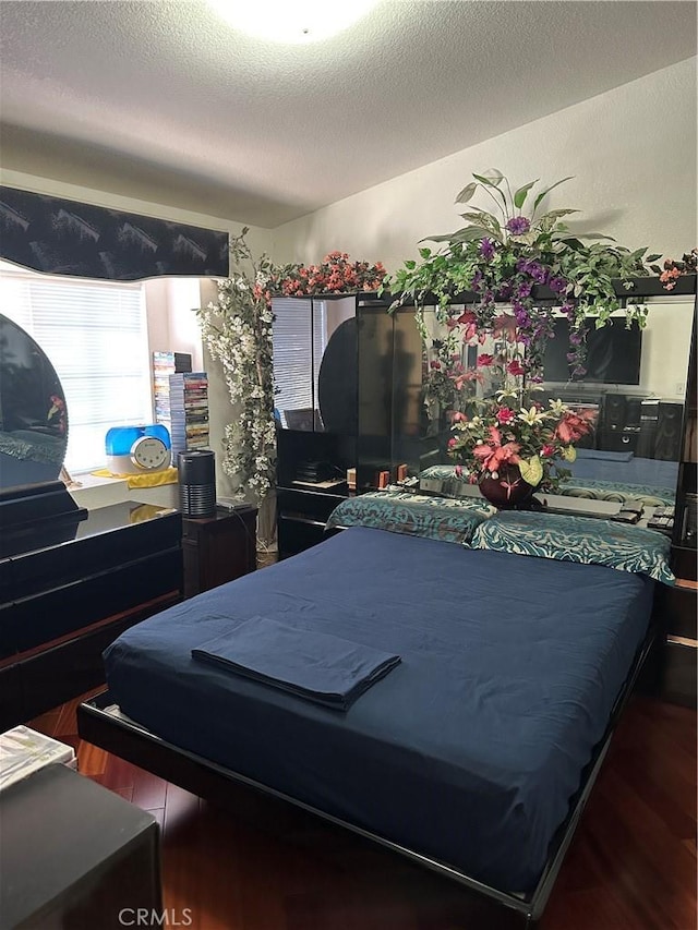 bedroom with a textured ceiling and wood finished floors