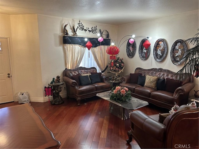 living room featuring wood-type flooring, baseboards, and a textured ceiling