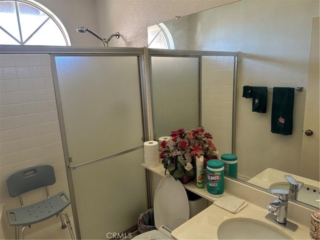 bathroom featuring a textured wall, a stall shower, and vanity