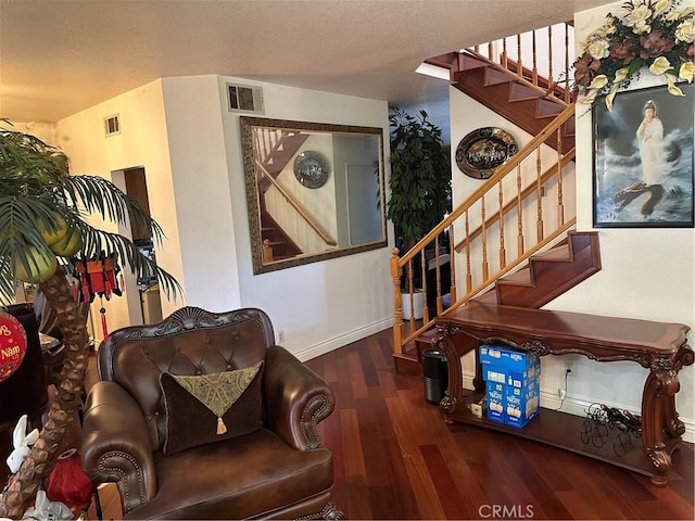 living room with visible vents, a textured ceiling, wood finished floors, baseboards, and stairs