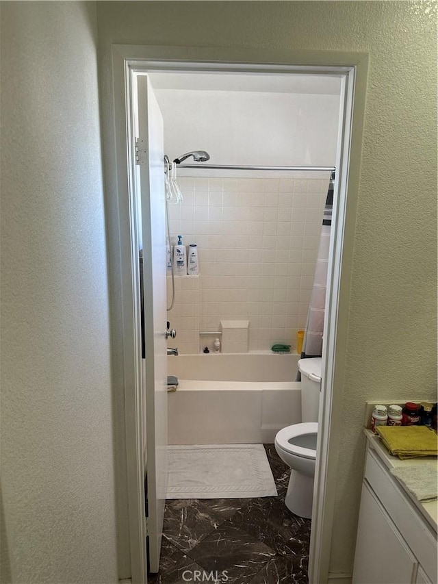 bathroom featuring toilet, marble finish floor, shower / bathtub combination with curtain, and a textured wall