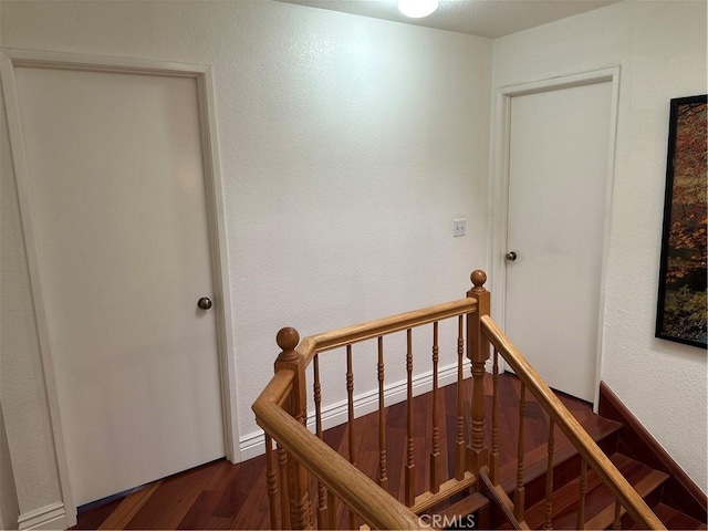 stairway with a textured wall and wood finished floors