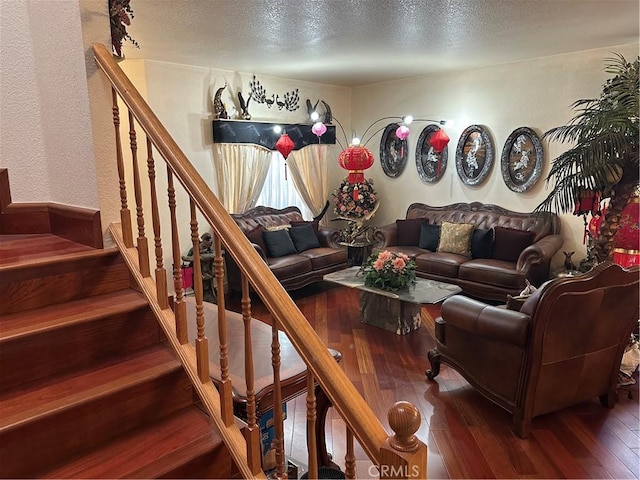 living room featuring a textured ceiling, a textured wall, stairway, and wood-type flooring