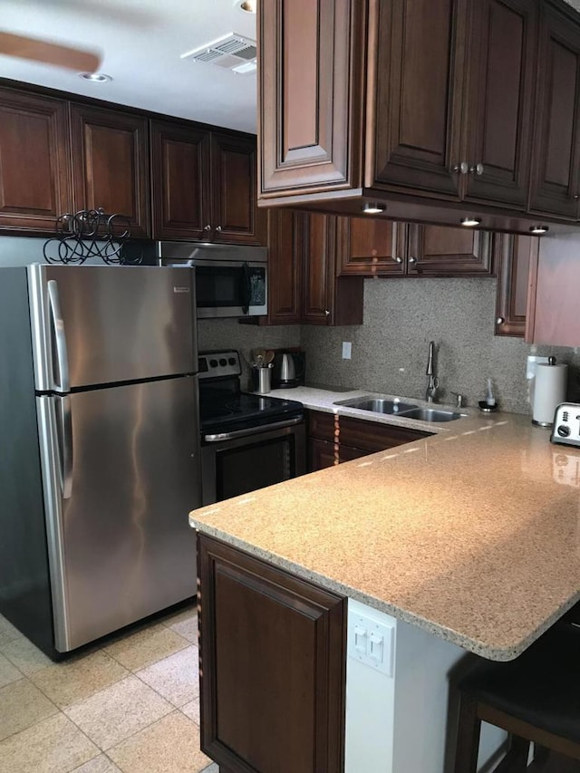 kitchen with a breakfast bar area, kitchen peninsula, sink, and appliances with stainless steel finishes