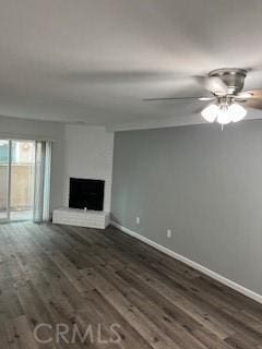 unfurnished living room featuring dark hardwood / wood-style flooring, a large fireplace, and ceiling fan