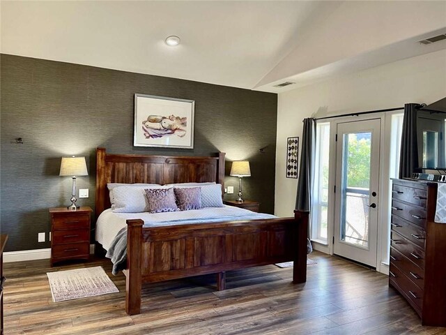 bedroom with access to exterior, hardwood / wood-style flooring, and lofted ceiling