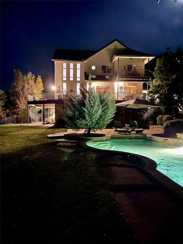 back house at twilight with a yard and a balcony