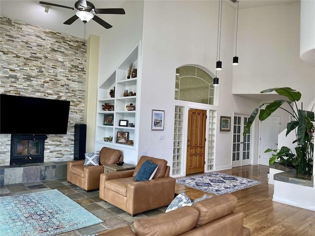 living room with hardwood / wood-style flooring, built in shelves, ceiling fan, and a high ceiling