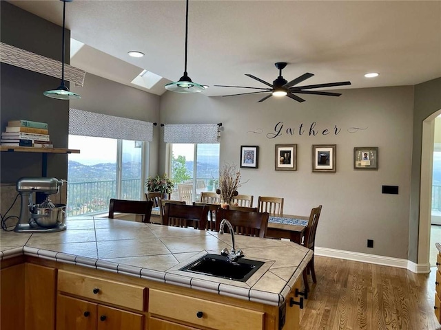 15223 Ledgewood Dr, Redding, CA 96001 - kitchen with baseboards, ceiling fan, dark wood-type flooring, tile counters, and a sink