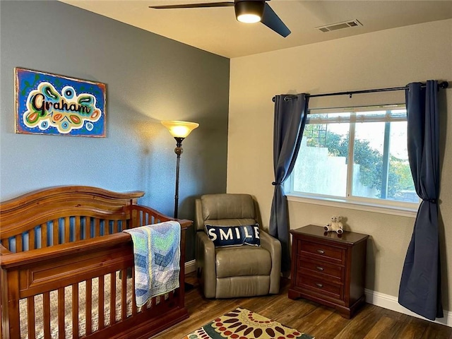 bedroom with ceiling fan, dark hardwood / wood-style floors, and a crib