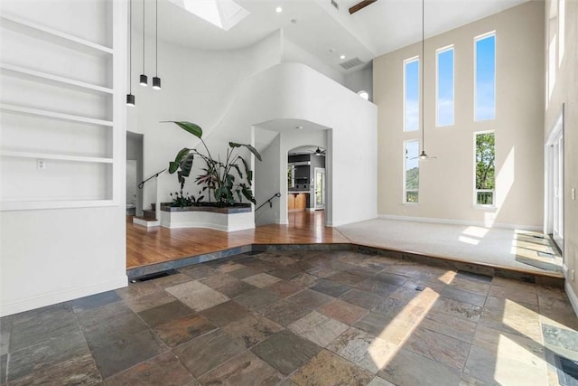 15223 Ledgewood Dr, Redding, CA 96001 - unfurnished living room featuring stone tile flooring, a high ceiling, baseboards, arched walkways, and ceiling fan