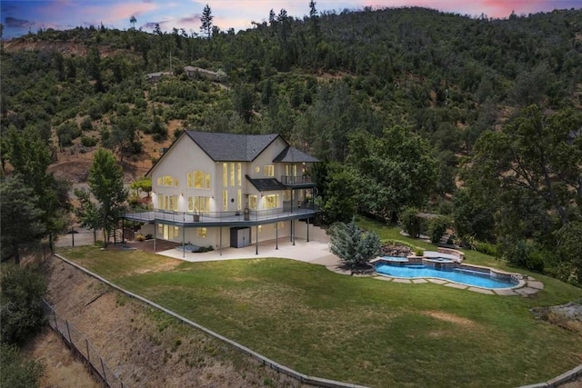 15223 Ledgewood Dr, Redding, CA 96001 - back of property featuring a patio area, a forest view, a pool with connected hot tub, stucco siding, and a wooden deck