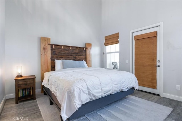 bedroom with hardwood / wood-style floors and a towering ceiling