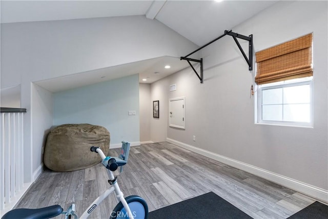 workout room with vaulted ceiling and light hardwood / wood-style flooring