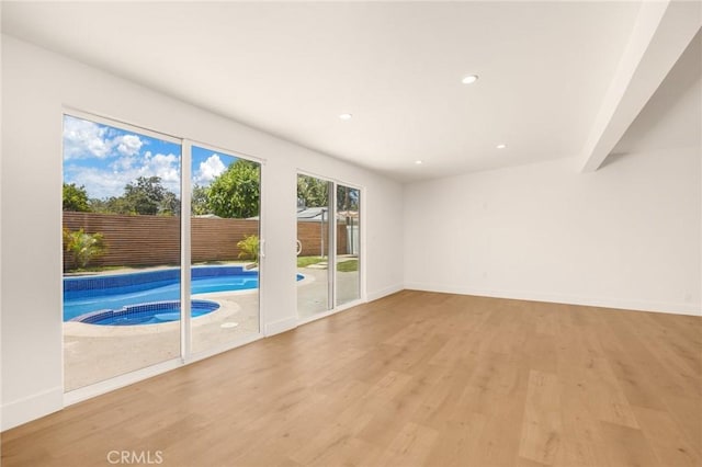 unfurnished living room with beam ceiling and light hardwood / wood-style flooring