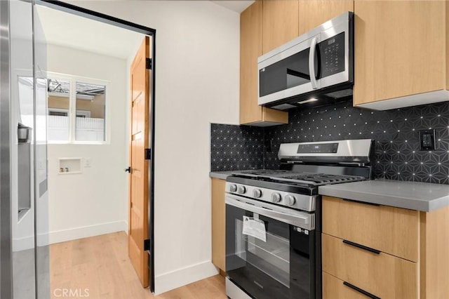 kitchen featuring tasteful backsplash, light brown cabinetry, light hardwood / wood-style flooring, and appliances with stainless steel finishes