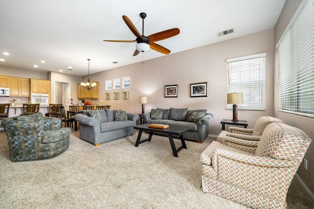 living room with ceiling fan with notable chandelier and light carpet