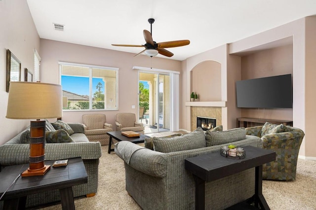 living room with ceiling fan, a fireplace, and light colored carpet