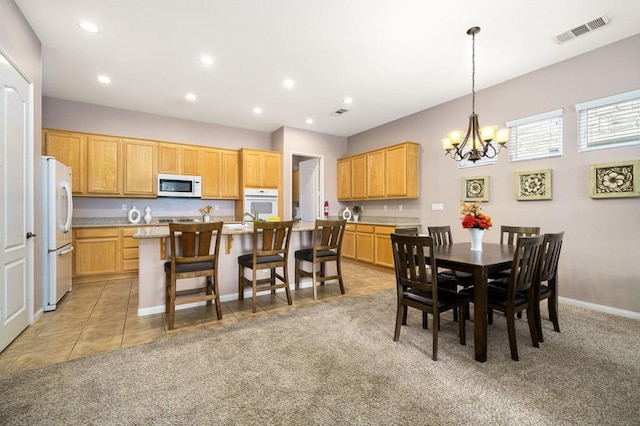 carpeted dining room featuring a notable chandelier and sink