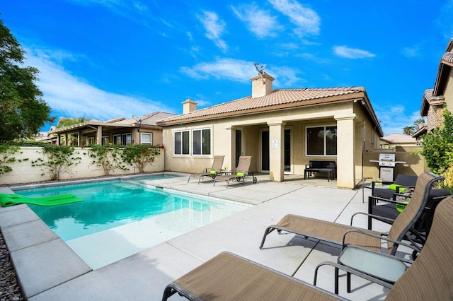 rear view of property with a fenced in pool and a patio