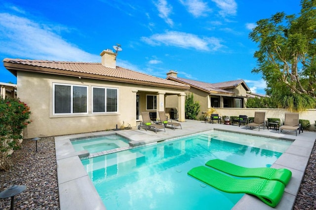 rear view of house featuring a patio area and a swimming pool with hot tub