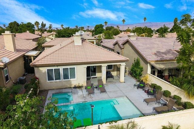 rear view of property featuring a patio area, a pool with hot tub, and central AC