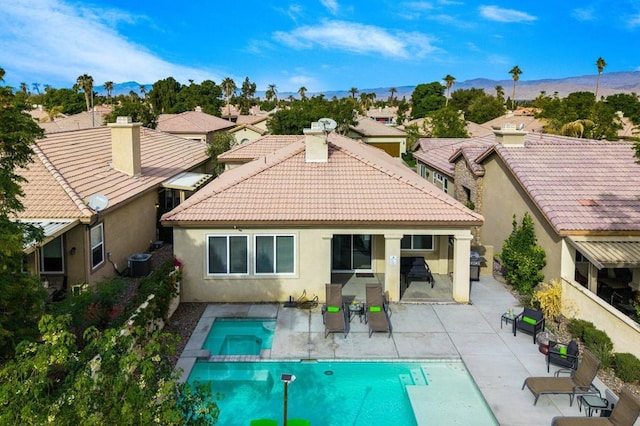 rear view of property featuring a patio area, central AC unit, and a pool with hot tub