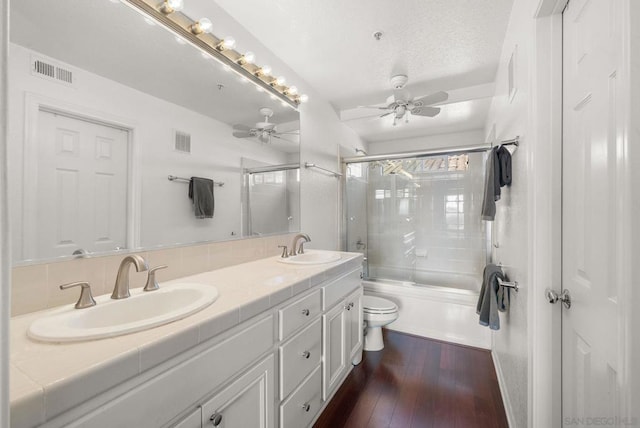 full bathroom featuring toilet, shower / bath combination with glass door, a textured ceiling, vanity, and hardwood / wood-style flooring