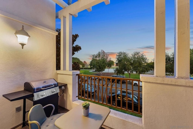 balcony at dusk featuring a grill