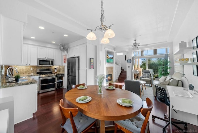 dining room featuring sink, ceiling fan with notable chandelier, and dark hardwood / wood-style floors