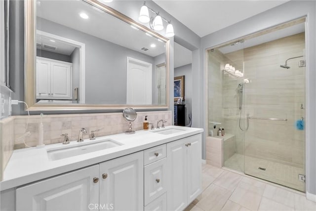 bathroom featuring tile patterned flooring, vanity, a shower with shower door, and backsplash