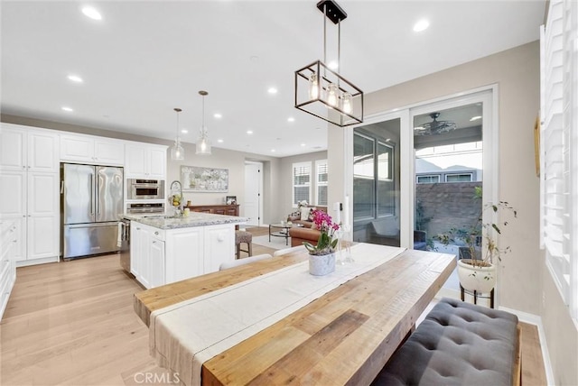 dining area with a notable chandelier, plenty of natural light, light hardwood / wood-style floors, and sink