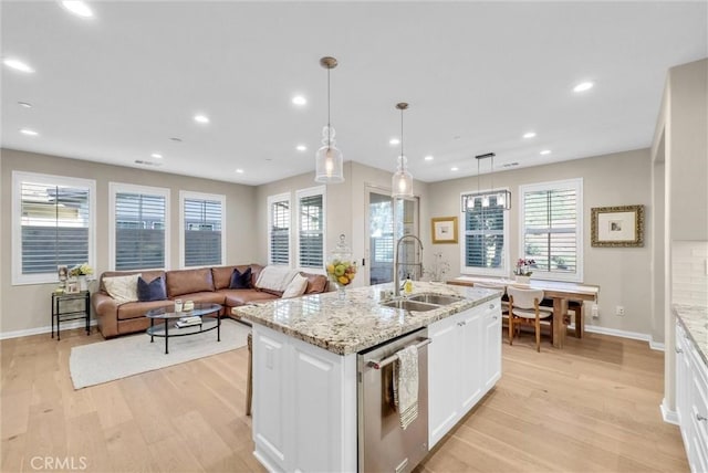 kitchen featuring white cabinetry, hanging light fixtures, stainless steel dishwasher, an island with sink, and light hardwood / wood-style floors