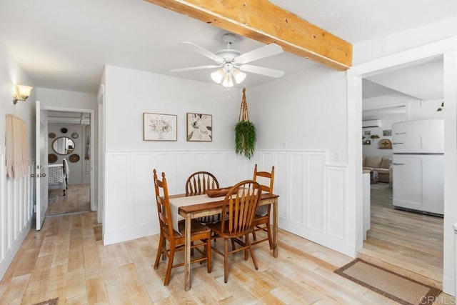 dining space with ceiling fan, light hardwood / wood-style flooring, and beamed ceiling