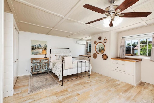 bedroom featuring a wall mounted AC, light hardwood / wood-style floors, and ceiling fan