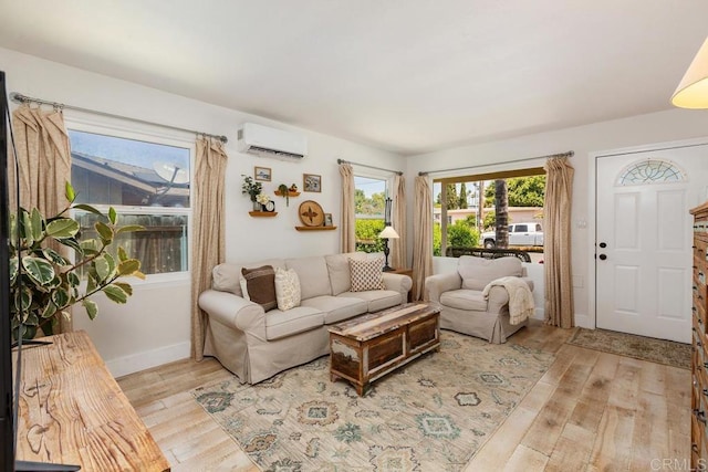living room featuring light wood-style floors, baseboards, and a wall mounted air conditioner