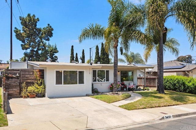 ranch-style home featuring fence, a front yard, and stucco siding