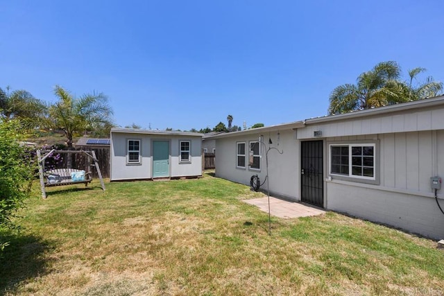 back of property featuring a lawn, fence, and an outdoor structure