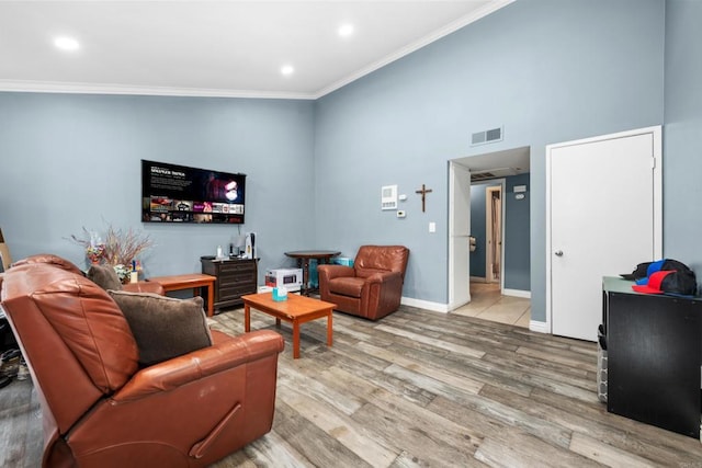 living room featuring a high ceiling, light hardwood / wood-style floors, and ornamental molding