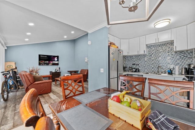 kitchen featuring white cabinets, sink, light wood-type flooring, ornamental molding, and appliances with stainless steel finishes