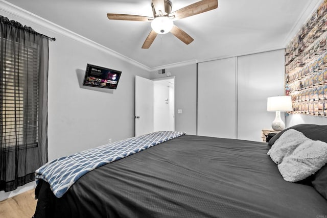 bedroom with hardwood / wood-style floors, ceiling fan, crown molding, and a closet