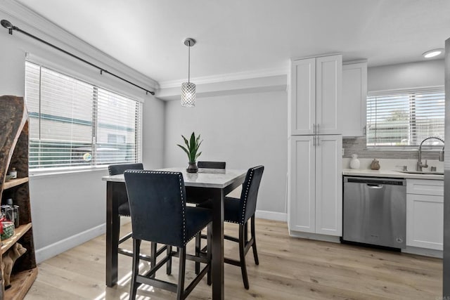 dining space featuring sink, light hardwood / wood-style floors, and ornamental molding