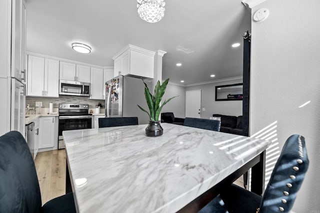 dining room with crown molding, light hardwood / wood-style flooring, and a chandelier