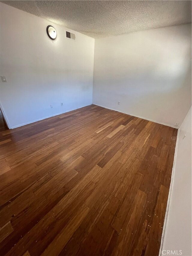 spare room with dark hardwood / wood-style floors and a textured ceiling