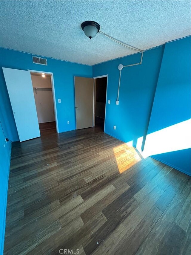 unfurnished room featuring a textured ceiling and dark hardwood / wood-style flooring