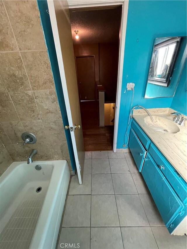 bathroom with vanity, tiled shower / bath, tile patterned floors, and a textured ceiling