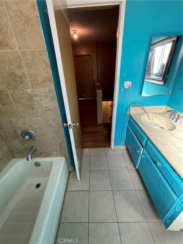 bathroom featuring tile patterned flooring, vanity, tiled shower / bath, and a textured ceiling