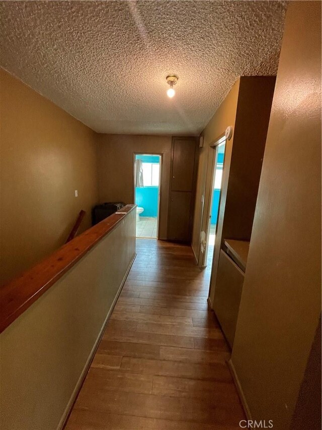 hall with hardwood / wood-style flooring and a textured ceiling