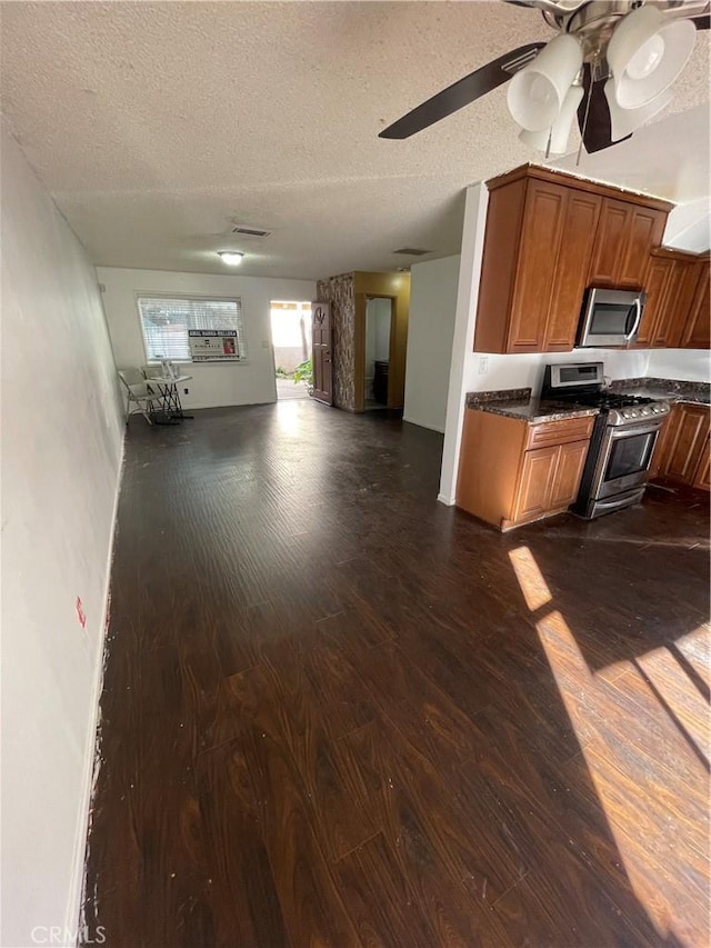 kitchen featuring ceiling fan, appliances with stainless steel finishes, dark hardwood / wood-style floors, and a textured ceiling