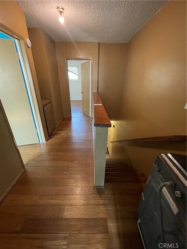 hallway with dark wood-type flooring and a textured ceiling